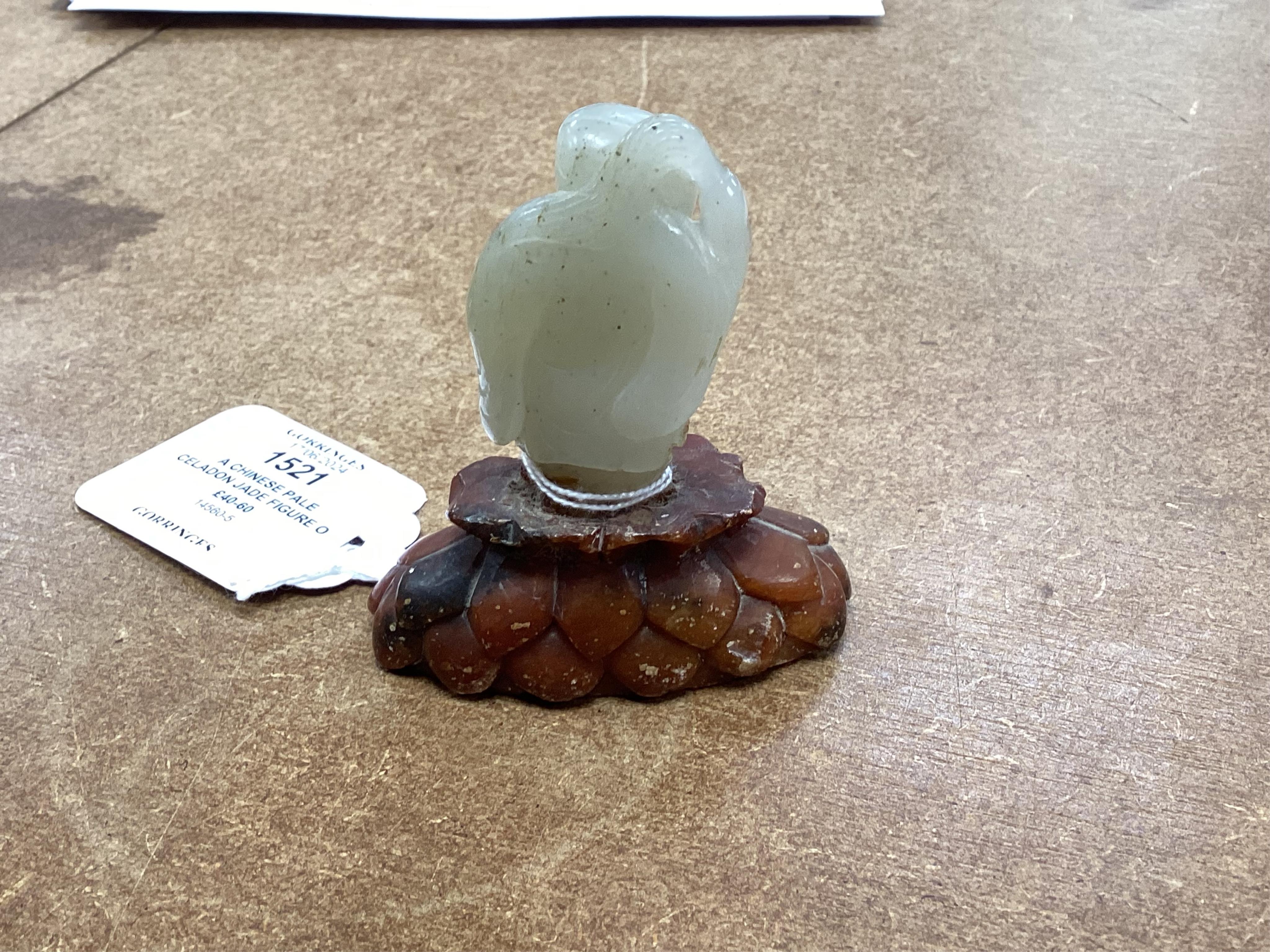 A Chinese pale celadon jade figure of a man holding a fly whisk, Qing dynasty, 5.2cm high, soapstone stand, total height 8cm high